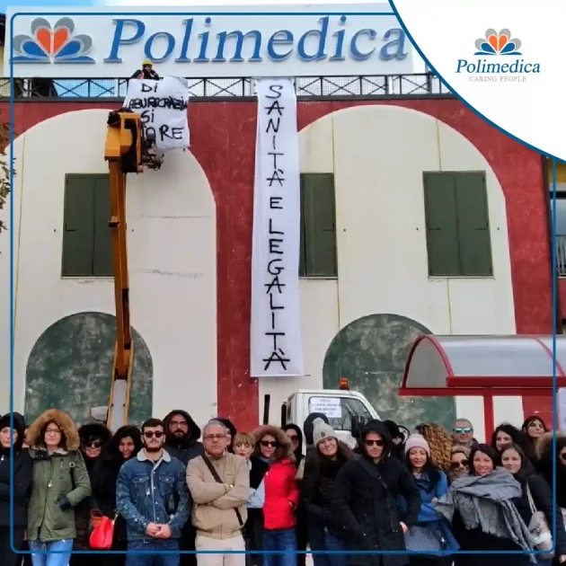 Immagine, con logo di Polimedica Melfi, di un gruppo di lavoratori del poliambulatorio durante un sit-in dedicato a "Sanità e legalità". Foto utilizzata per la pagina Difendiamo Polimedica.