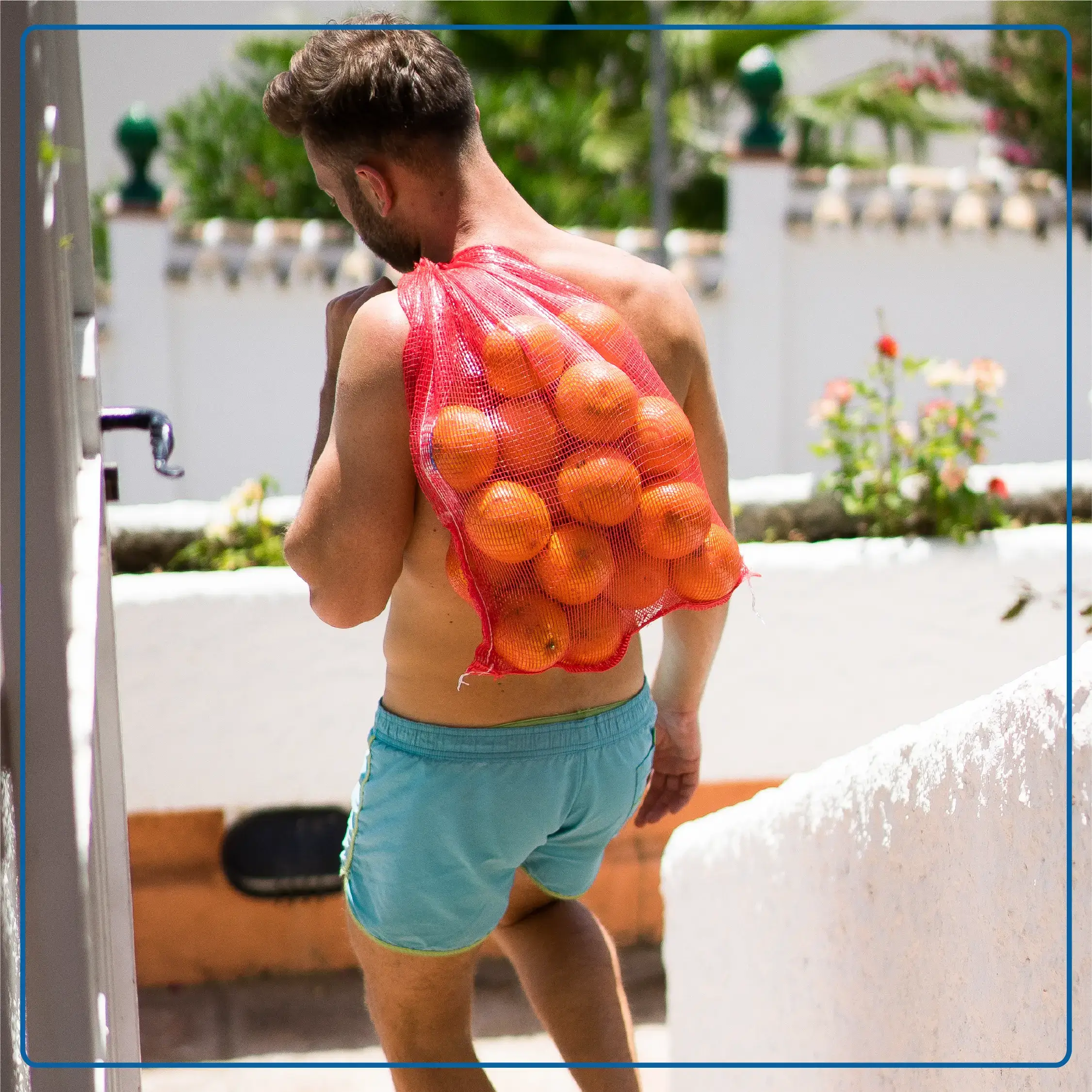 Immagine di un uomo in costume con un sacco di arance sulle spalle. Immagine rappresentativa dello stile di vita mediterraneo. Foto di accompagnamento all'articolo "La Dieta Mediterranea in un’ottica di Nutrizione Clinica".