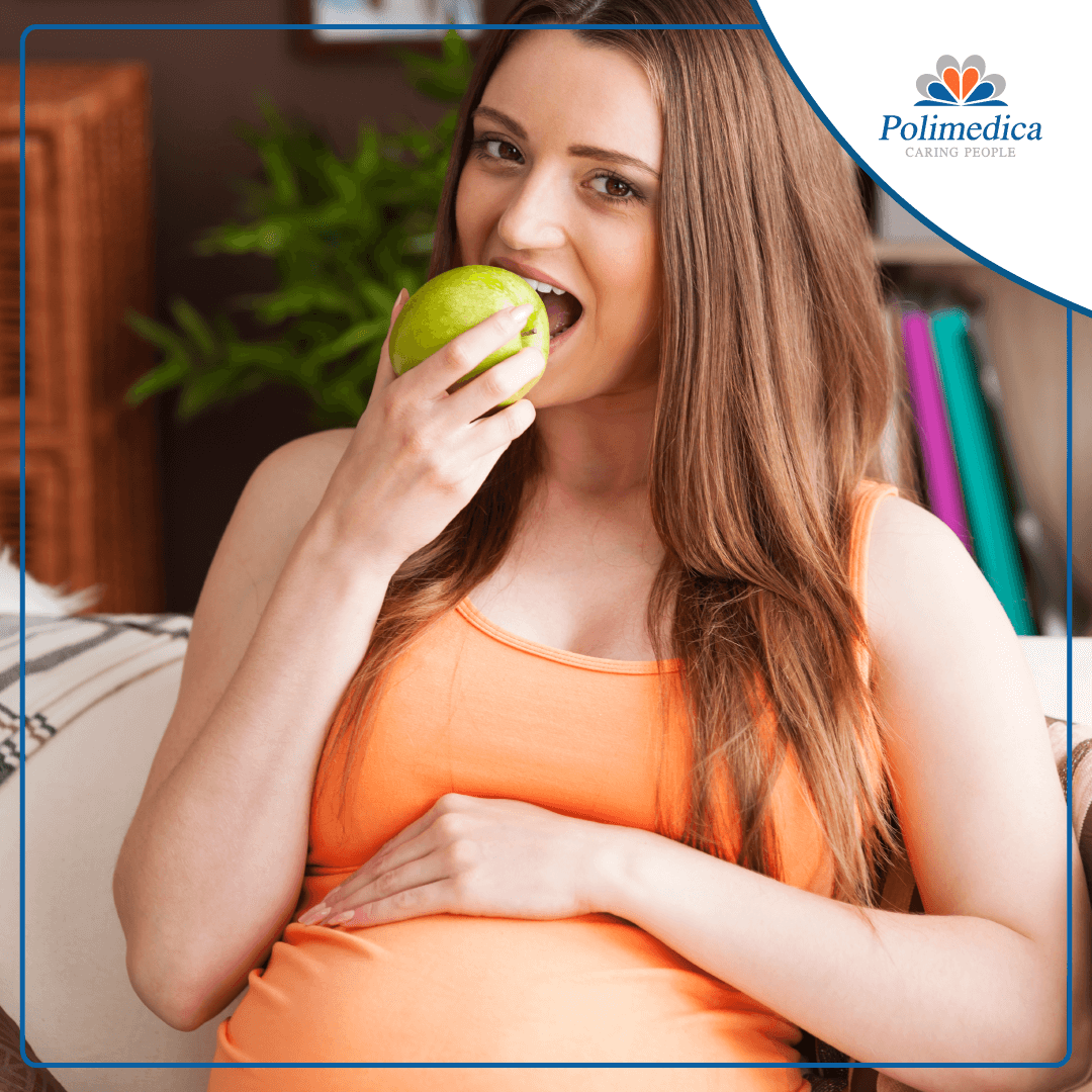 Foto, con logo di Polimedica Melfi, di una donna incinta che mangia una mela. Immagine di accompagnamento all'articolo dedicato a "Alimentazione e fertilità".