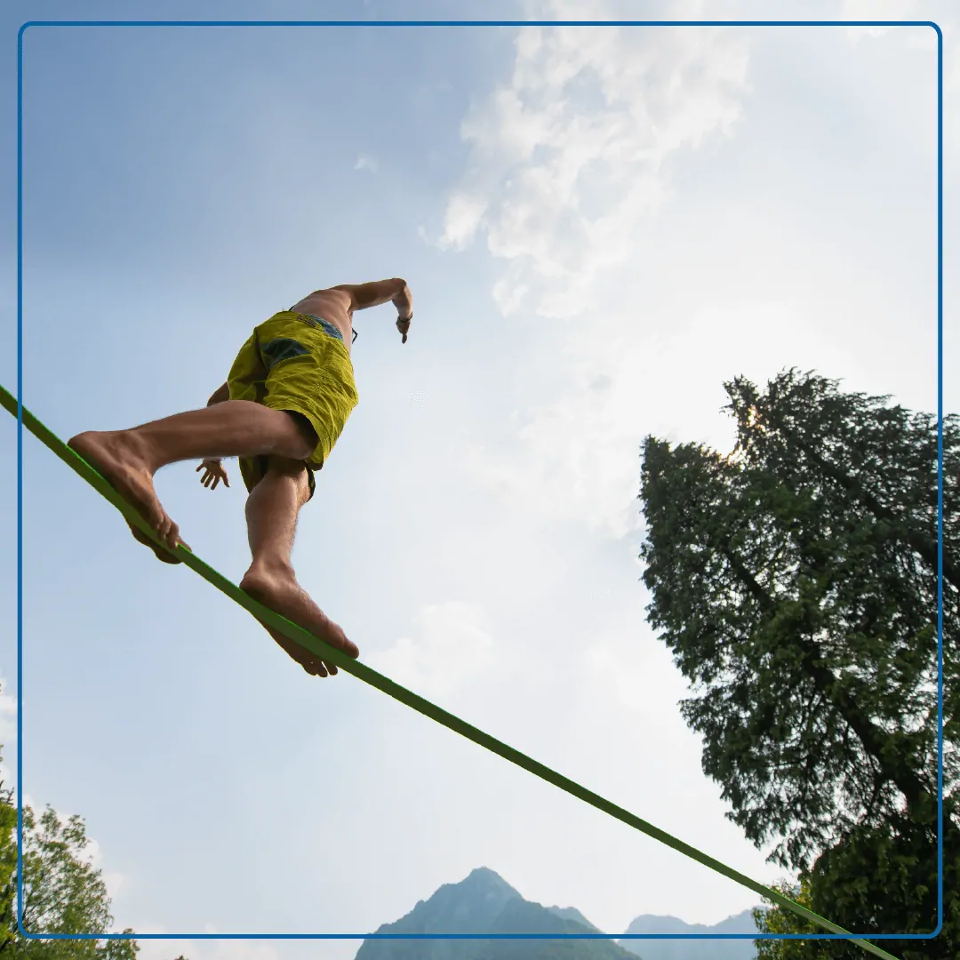 Immagine di un uomo in equilibrio su una corda elastica che esegue uno esercizio di slackline. Foto utilizzata per la pagina Esame vestibolare.