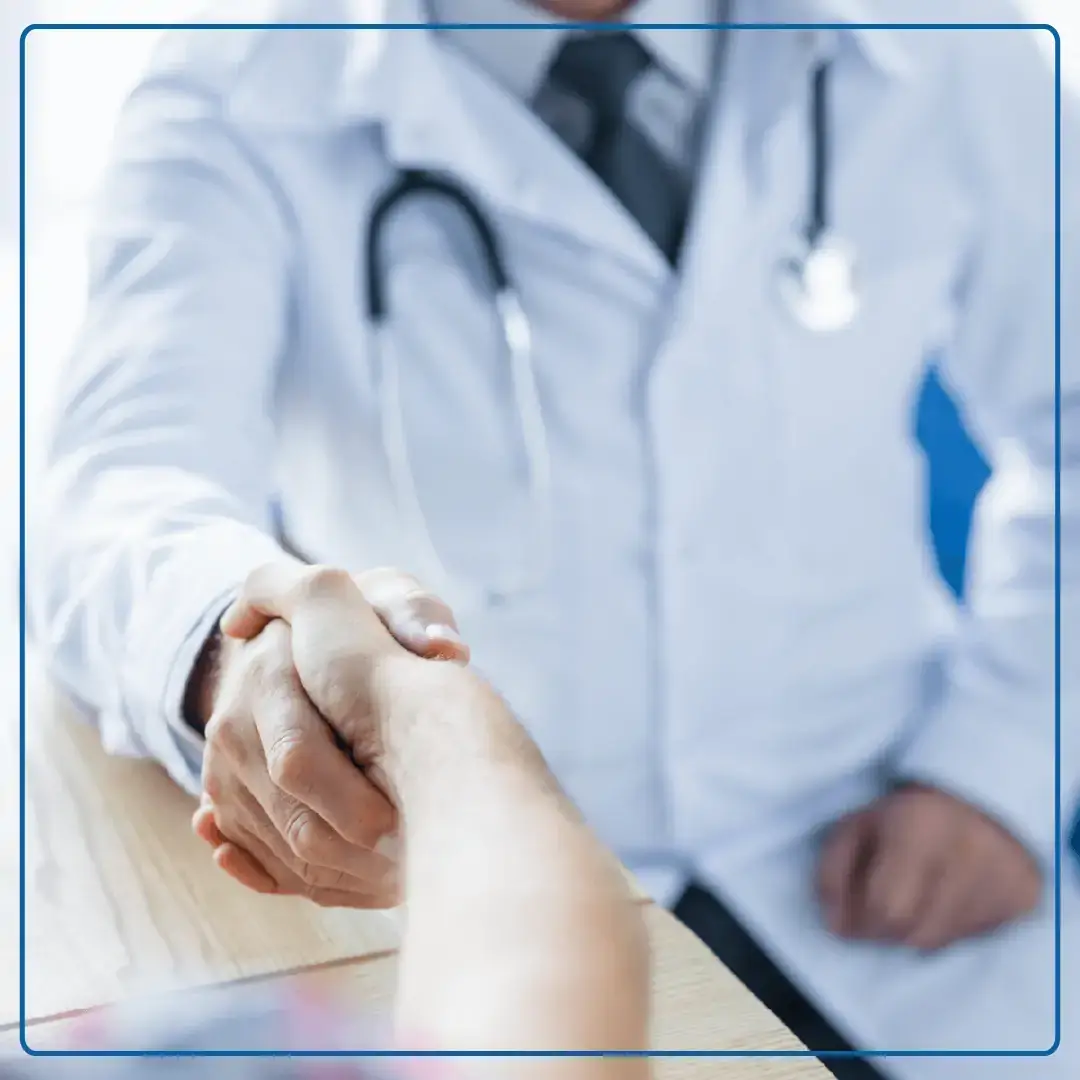 Foto di un medico che stringe la mano ad un paziente seduto alla scrivania. Immagine utilizzata per la pagina Visita chirurgica ambulatoriale.